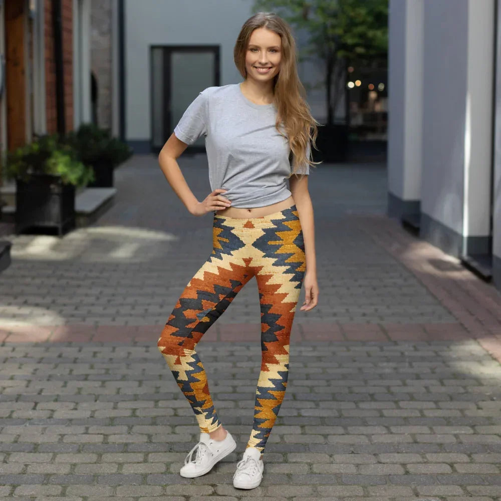 Smiling woman in colorful geometric print leggings and gray t-shirt standing on cobblestone street