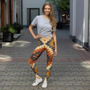 Smiling woman in colorful geometric print leggings and gray t-shirt standing on cobblestone street