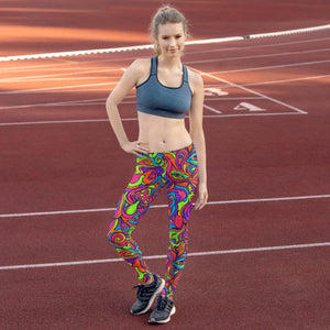 Woman standing on outdoor running track wearing colorful psychedelic leggings and a dark sports bra