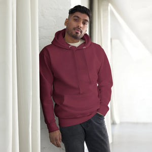Man wearing maroon unisex premium pullover hoodie posing indoors against white brick wall