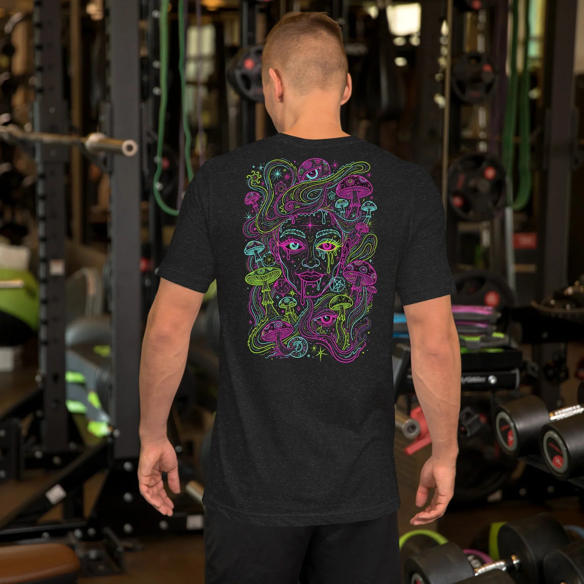 Man wearing black t-shirt with colorful psychedelic Medusa design at gym with weights