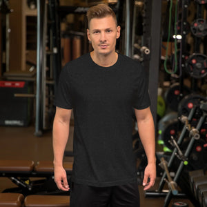 Man wearing plain black heather unisex staple t-shirt in gym with weightlifting equipment