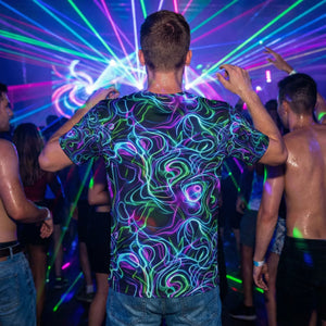 Person wearing neon psychedelic t-shirt dancing at vibrant laser-lit party with crowd