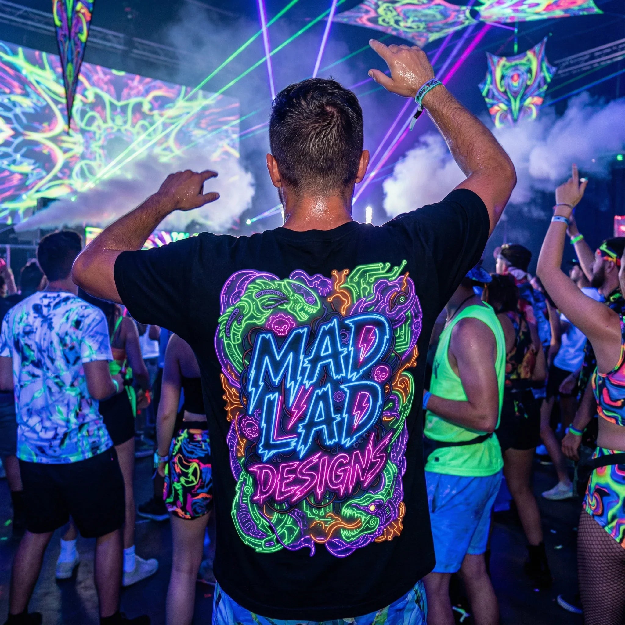 Man wearing psychedelic Mad Lad Designs neon graphic T-shirt at vibrant electronic music festival with colorful laser lights