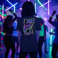 Person wearing black tee with neon dragon design on back at vibrant glow-in-the-dark dance party