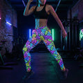 Woman in neon geometric psychedelic leggings and black sports bra poses in colorful gym