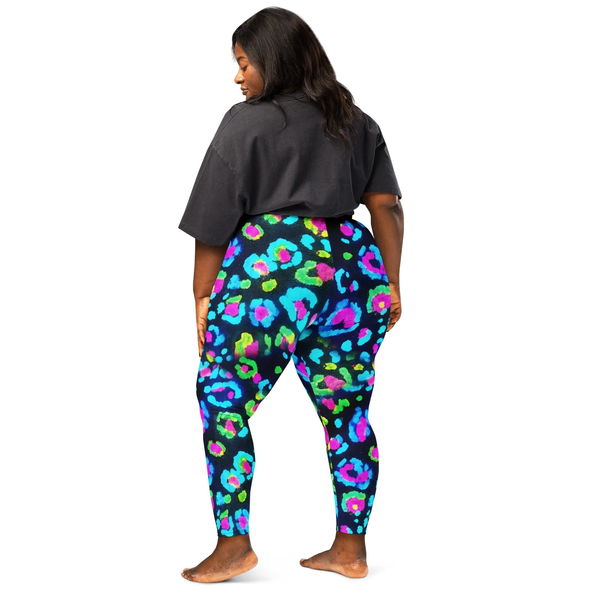 Plus size woman wearing vibrant neon multicolor leopard print leggings and a black oversized t-shirt standing barefoot