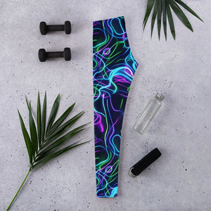 Flat lay of vibrant psychedelic neon print leggings beside dumbbells, water bottle, yoga strap, and palm leaves on concrete floor