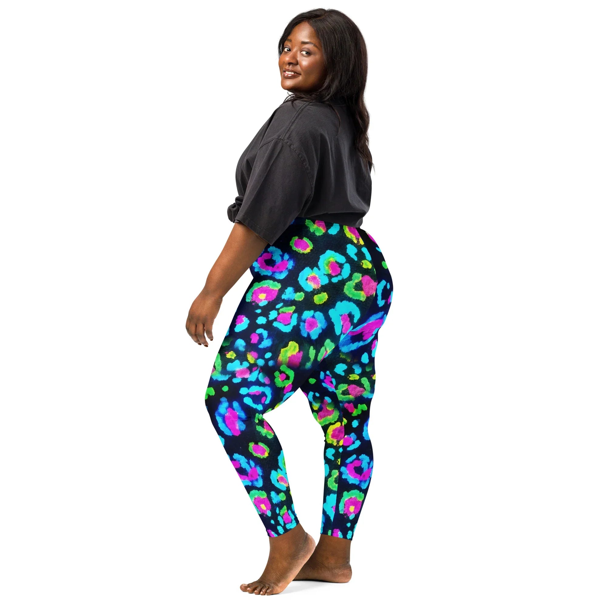 Plus-size woman wearing vibrant neon leopard print leggings and black oversized t-shirt on white background