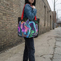 Woman wearing denim jacket carries Mad Lad Designs psychedelic neon art tote bag on city street