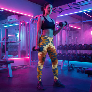 Woman in neon-lit gym wearing vibrant geometric patterned leggings and black sports bra holding dumbbells
