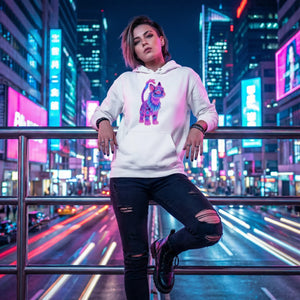Young woman in ripped jeans and white hoodie with colorful cat graphic posing on city street at night with neon lights