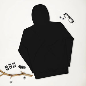 Black unisex premium pullover hoodie displayed flat with Halloween-themed decor, black glasses, and branch accents