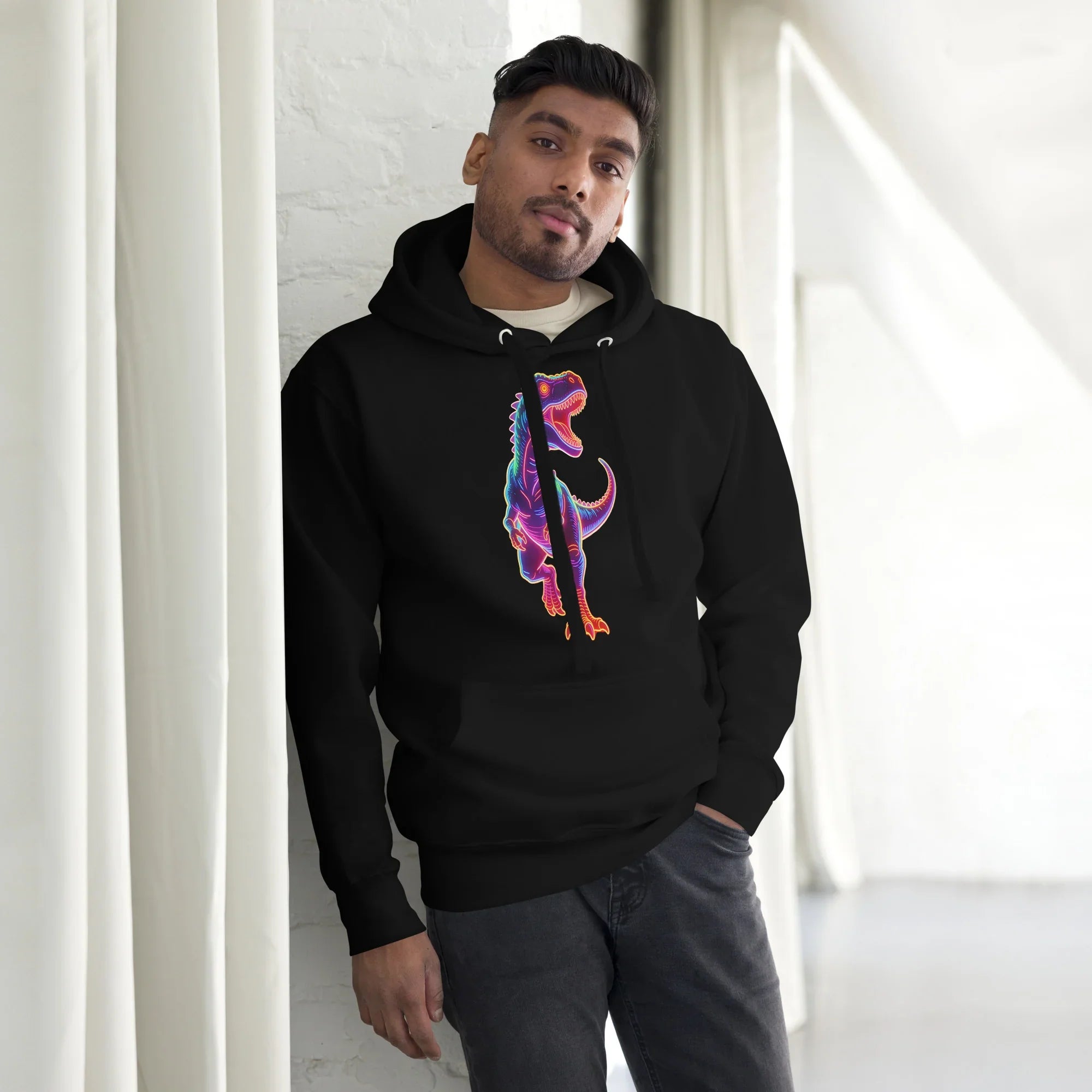 Young man wearing a black hoodie with a vibrant neon dinosaur graphic, standing indoors