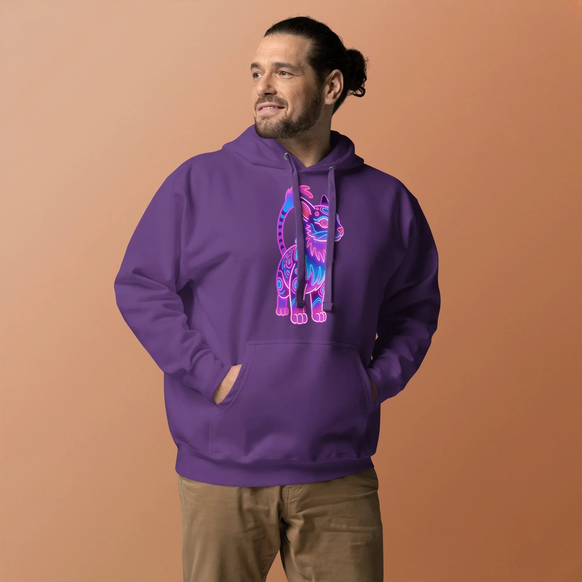 Man wearing purple pullover hoodie with neon cat graphic, standing against beige background