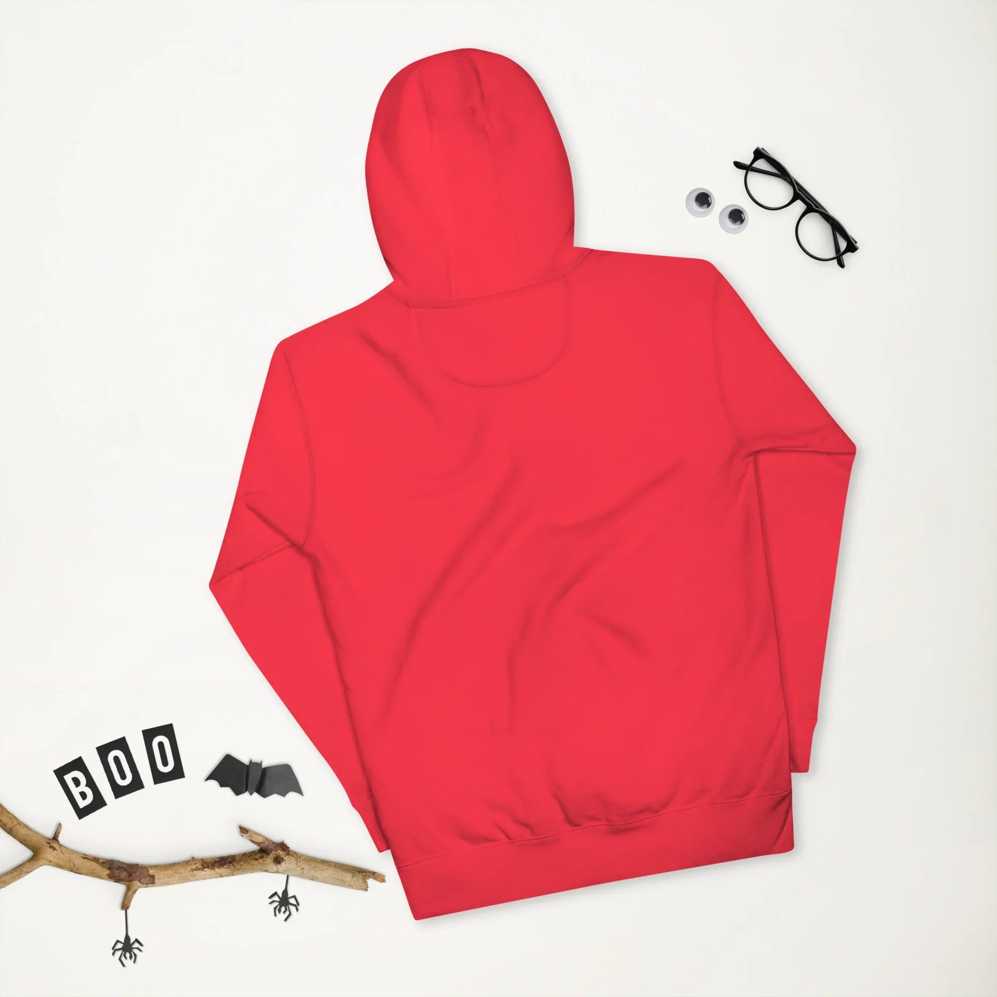 Back view of unisex premium red pullover hoodie on white background with Halloween-themed props