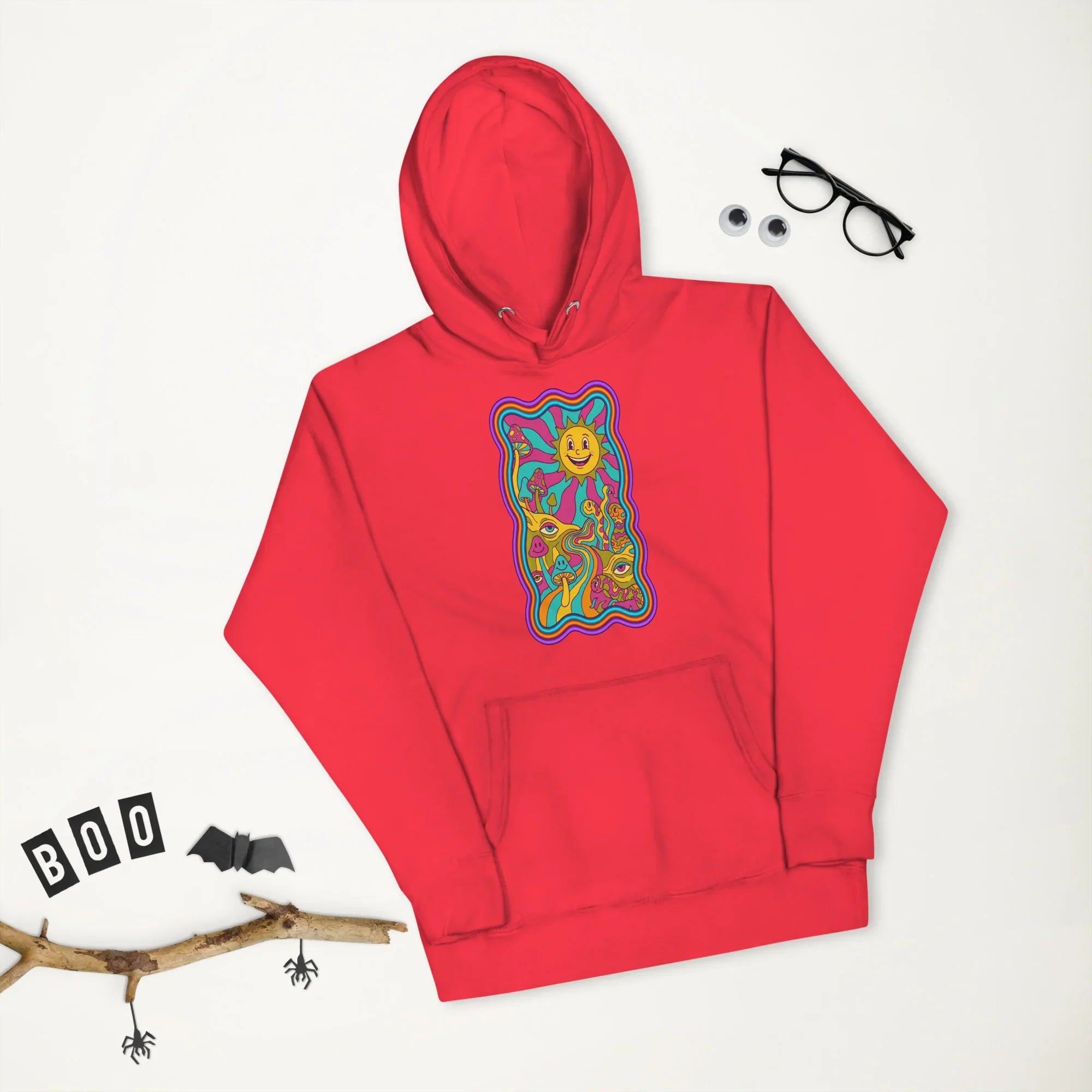 Unisex premium red pullover hoodie with psychedelic colorful mushroom and sun design on front, styled with Halloween decor