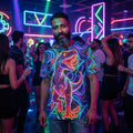 Man wearing neon psychedelic dinosaur T-shirt in vibrant nightclub with colorful neon lights