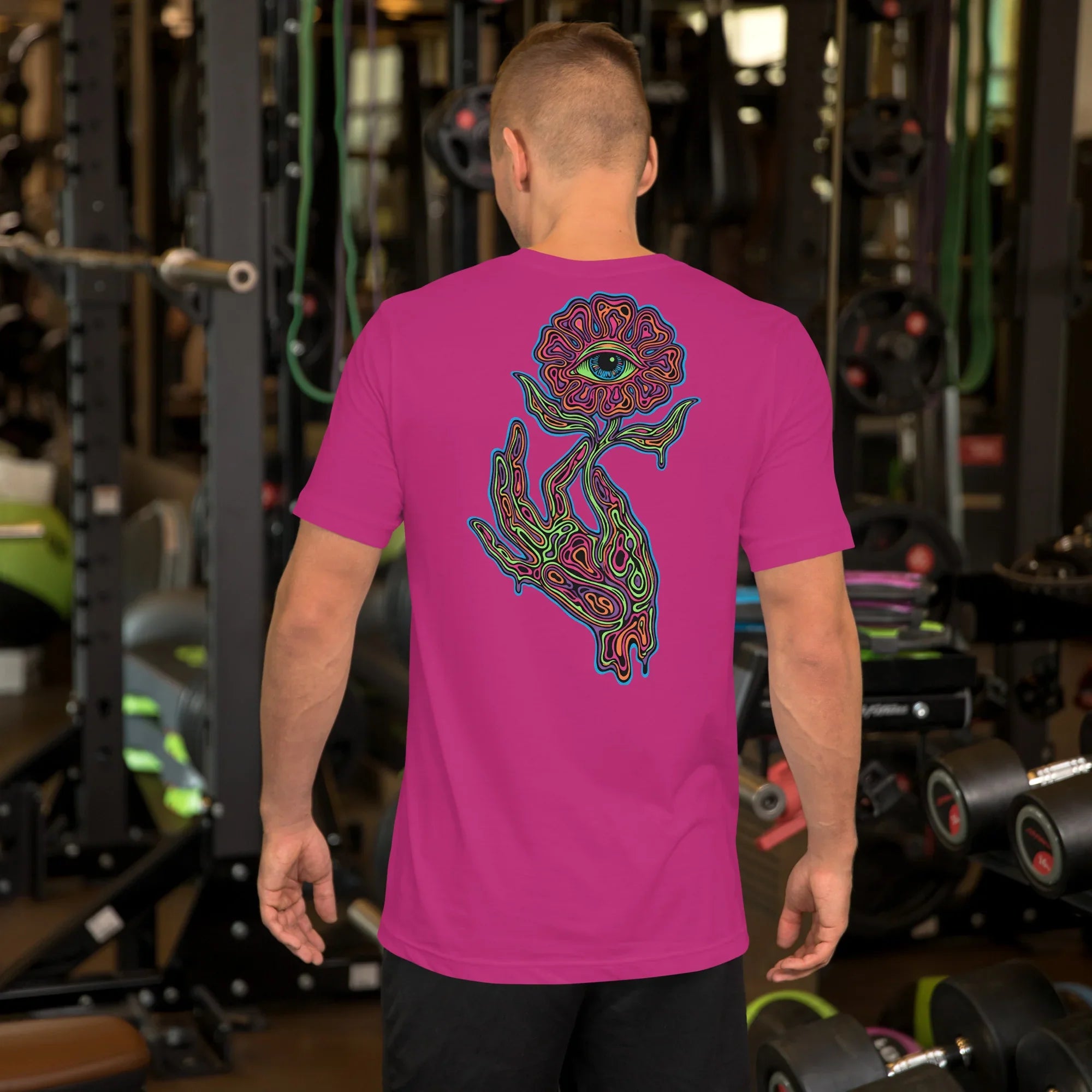 Man in gym wearing bright berry unisex T-shirt with psychedelic eye-flower and hand graphic on back