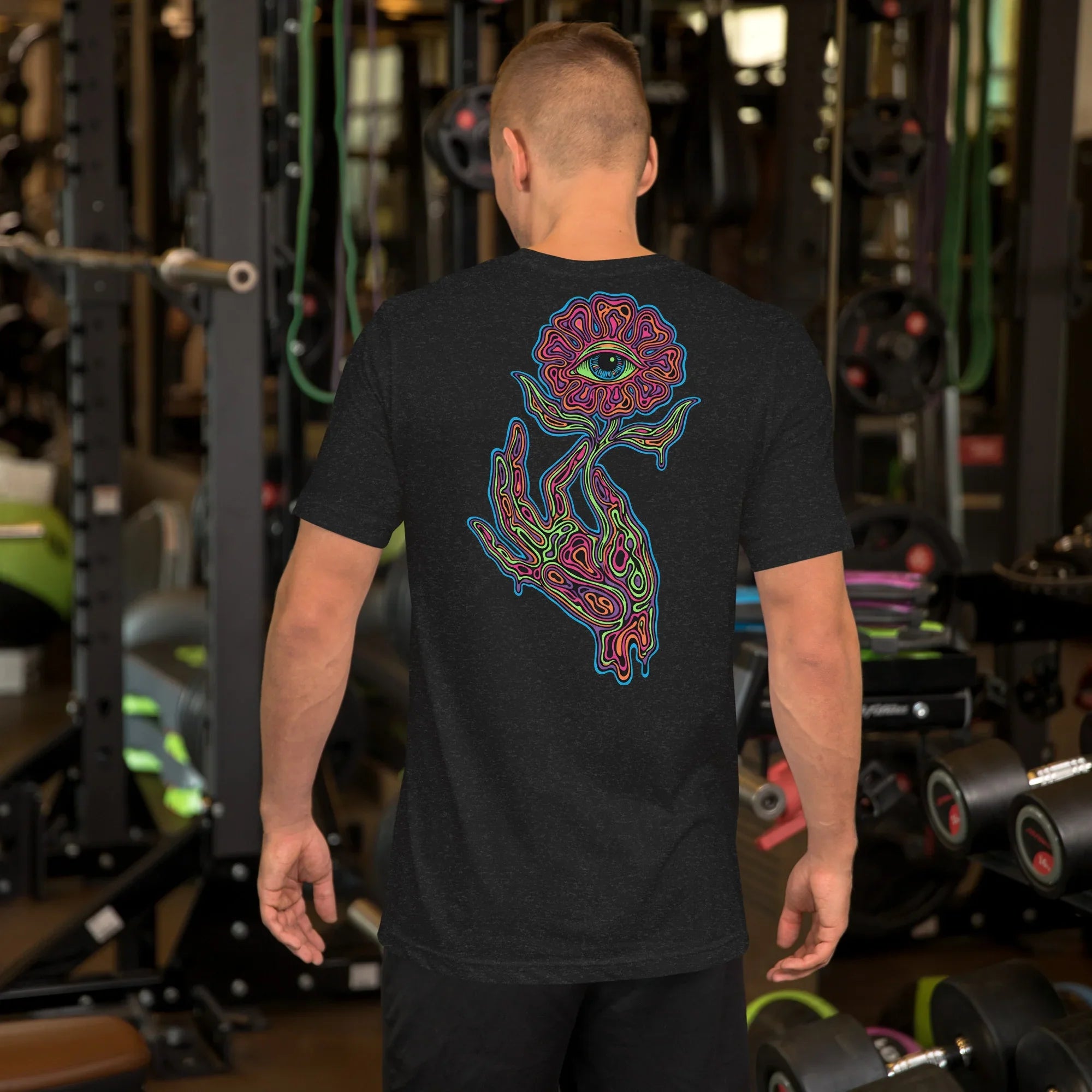 man in gym wearing black heather unisex t-shirt with psychedelic neon hand and eye flower design on back