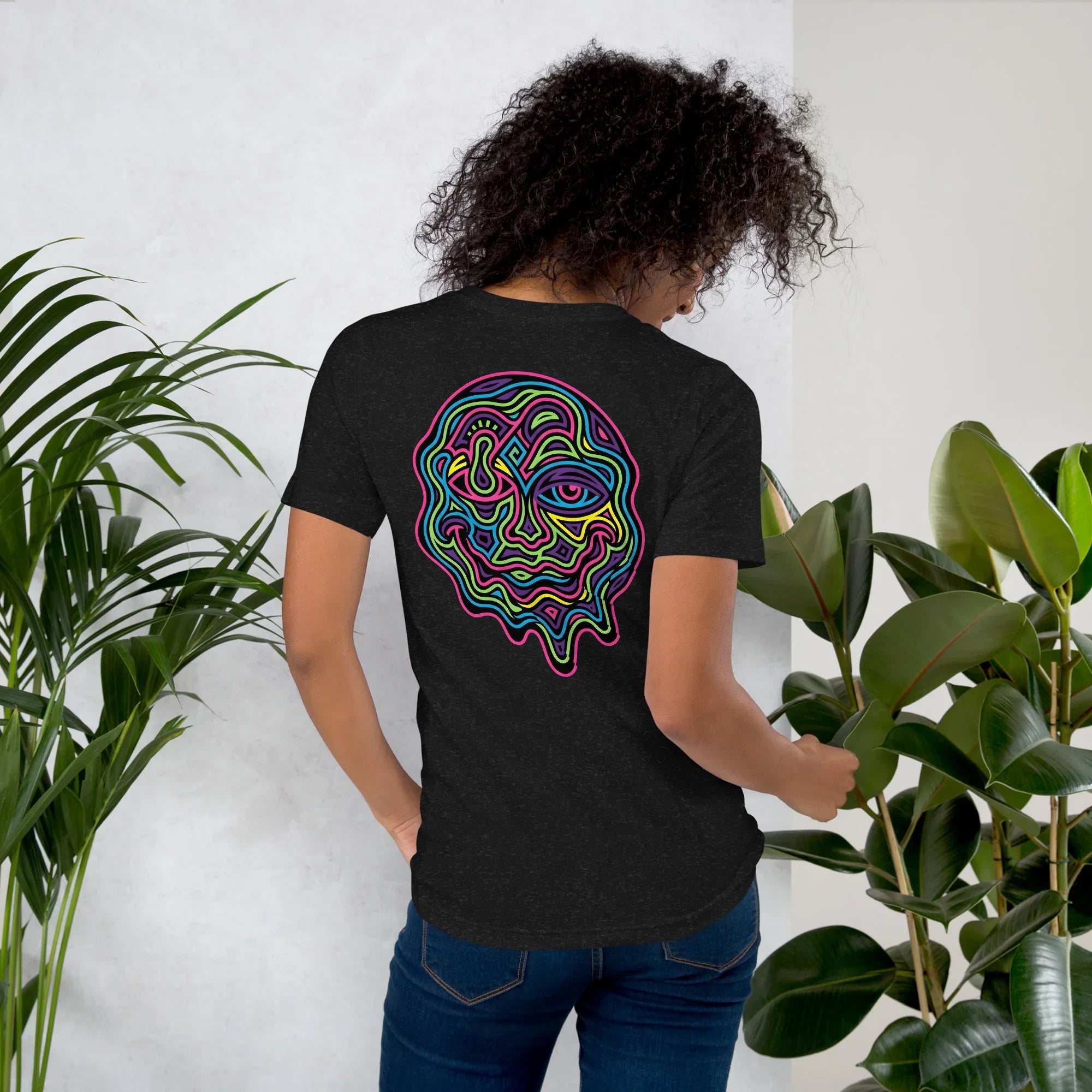Woman wearing black heather unisex staple t-shirt with vibrant psychedelic neon abstract face design on back