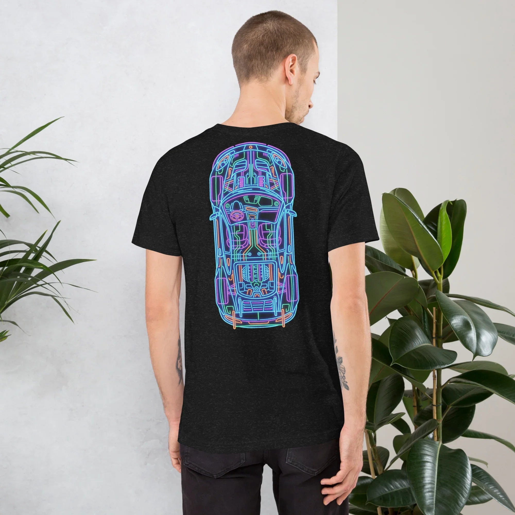 Man wearing black heather unisex t-shirt with colorful neon car blueprint design on back in indoor setting