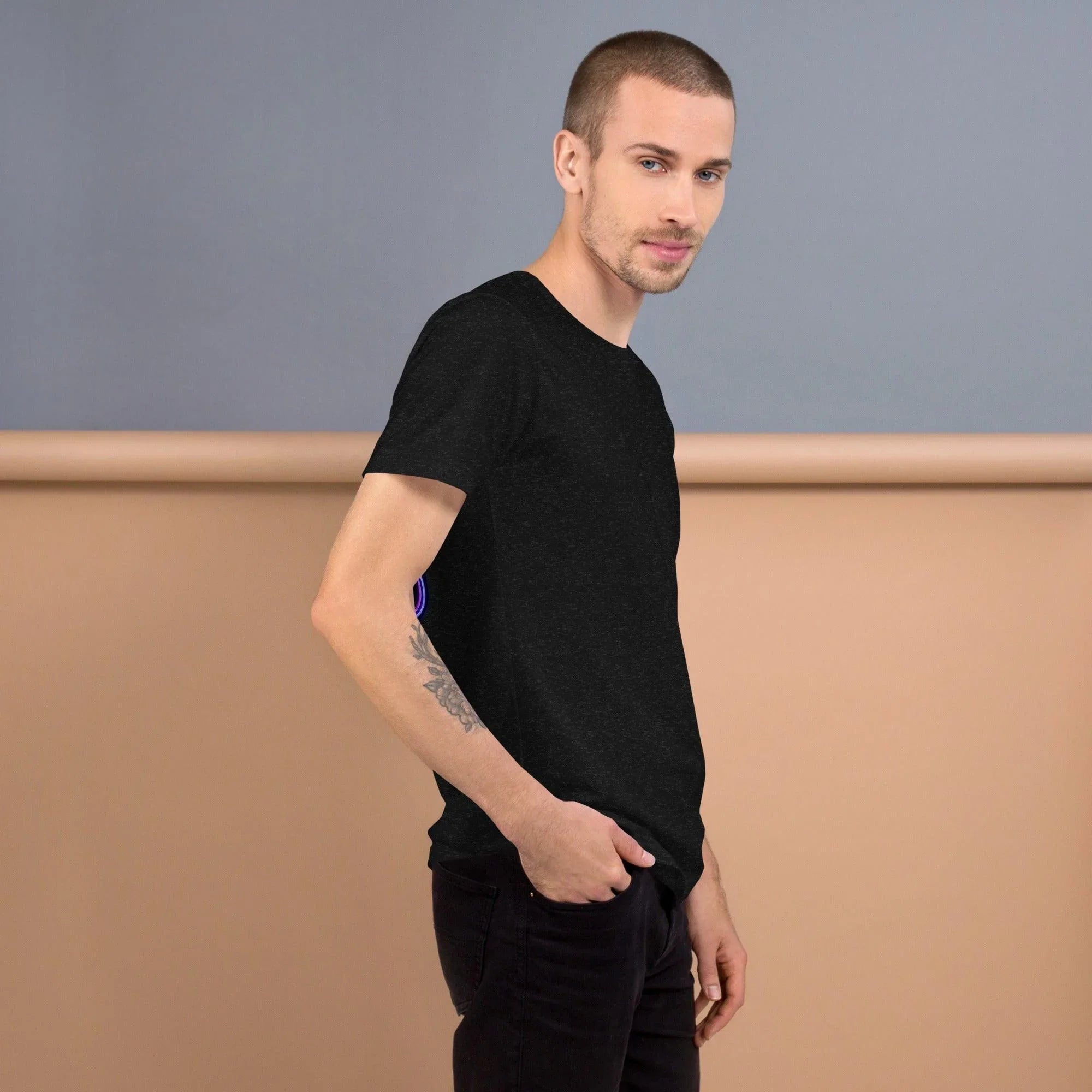 Model wearing black heather unisex staple t-shirt with short sleeves against beige and gray backdrop