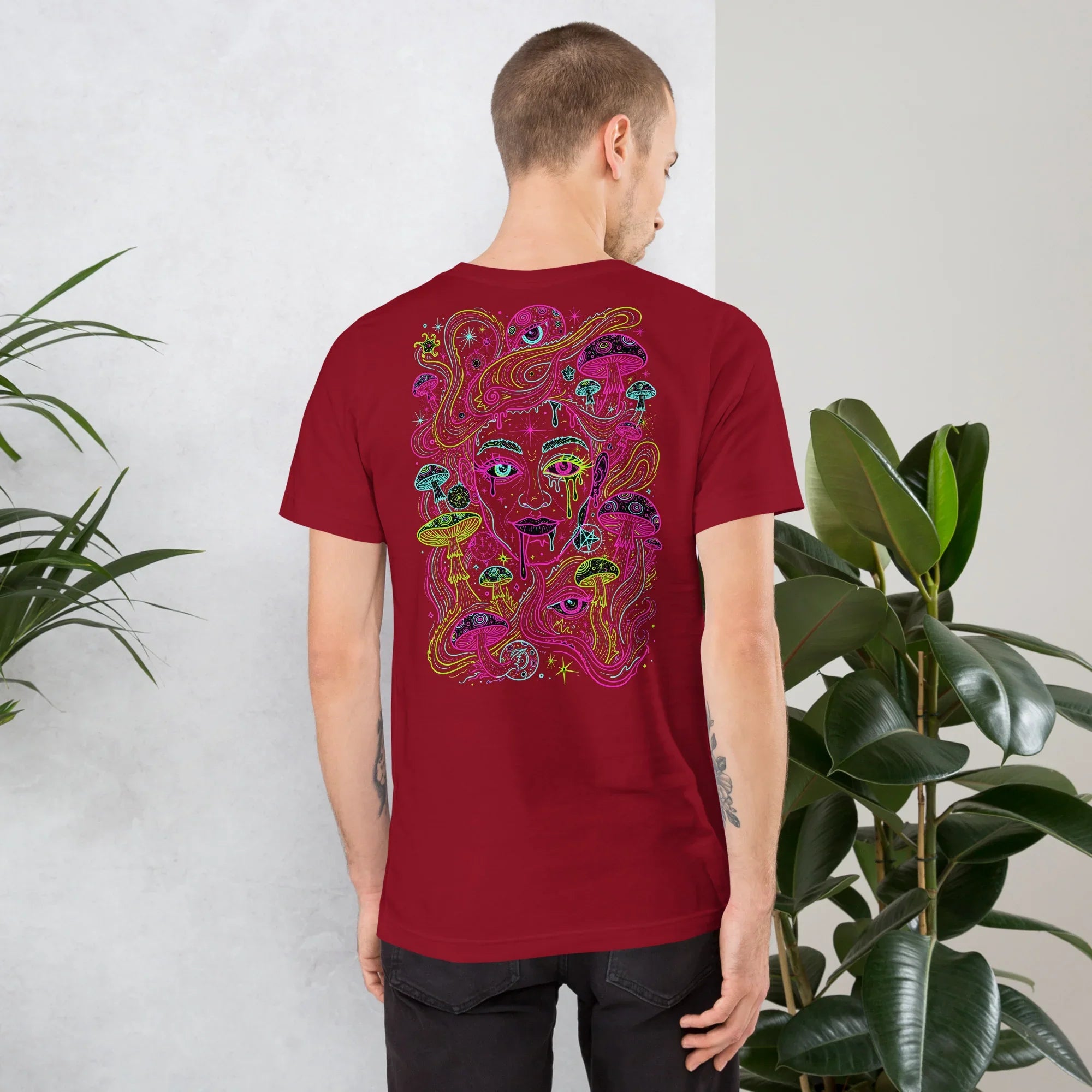 Man wearing cardinal red unisex T-shirt with psychedelic neon mushroom and face artwork on back