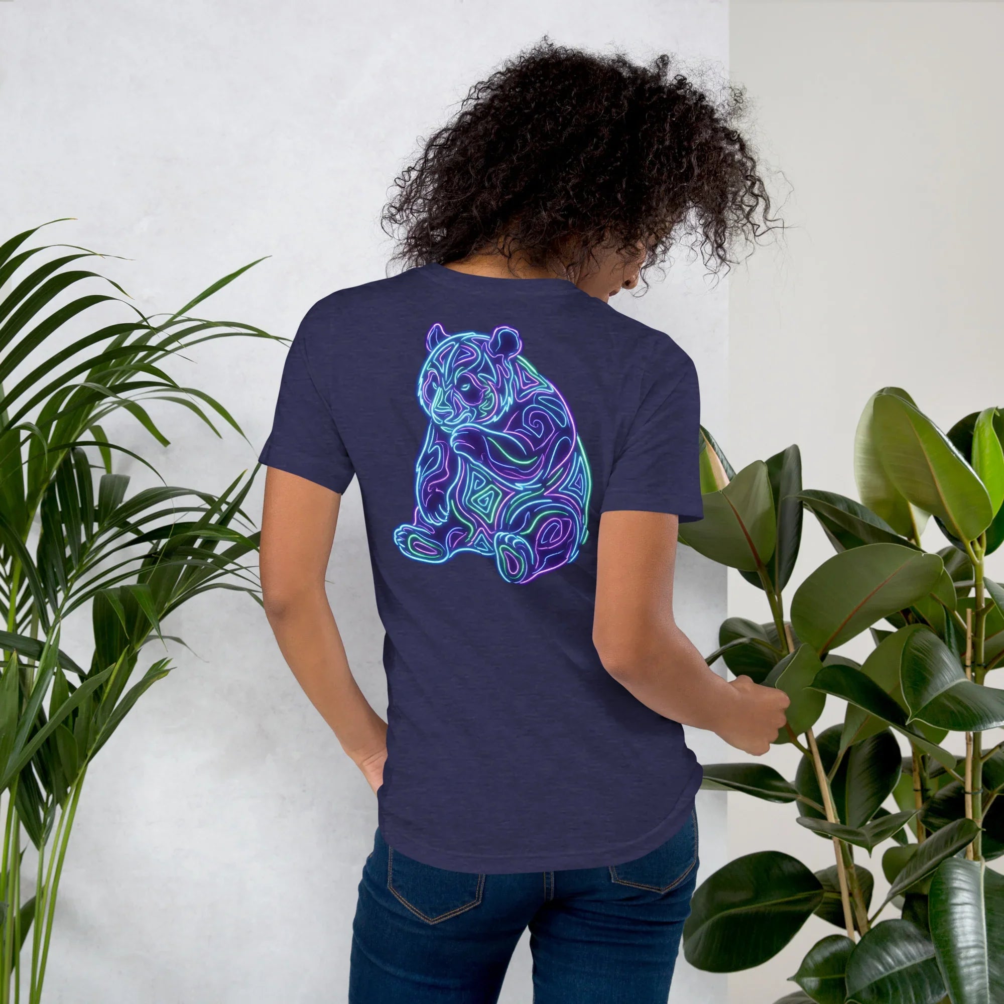 Person wearing midnight navy unisex t-shirt with neon psychedelic tiger design, surrounded by green plants