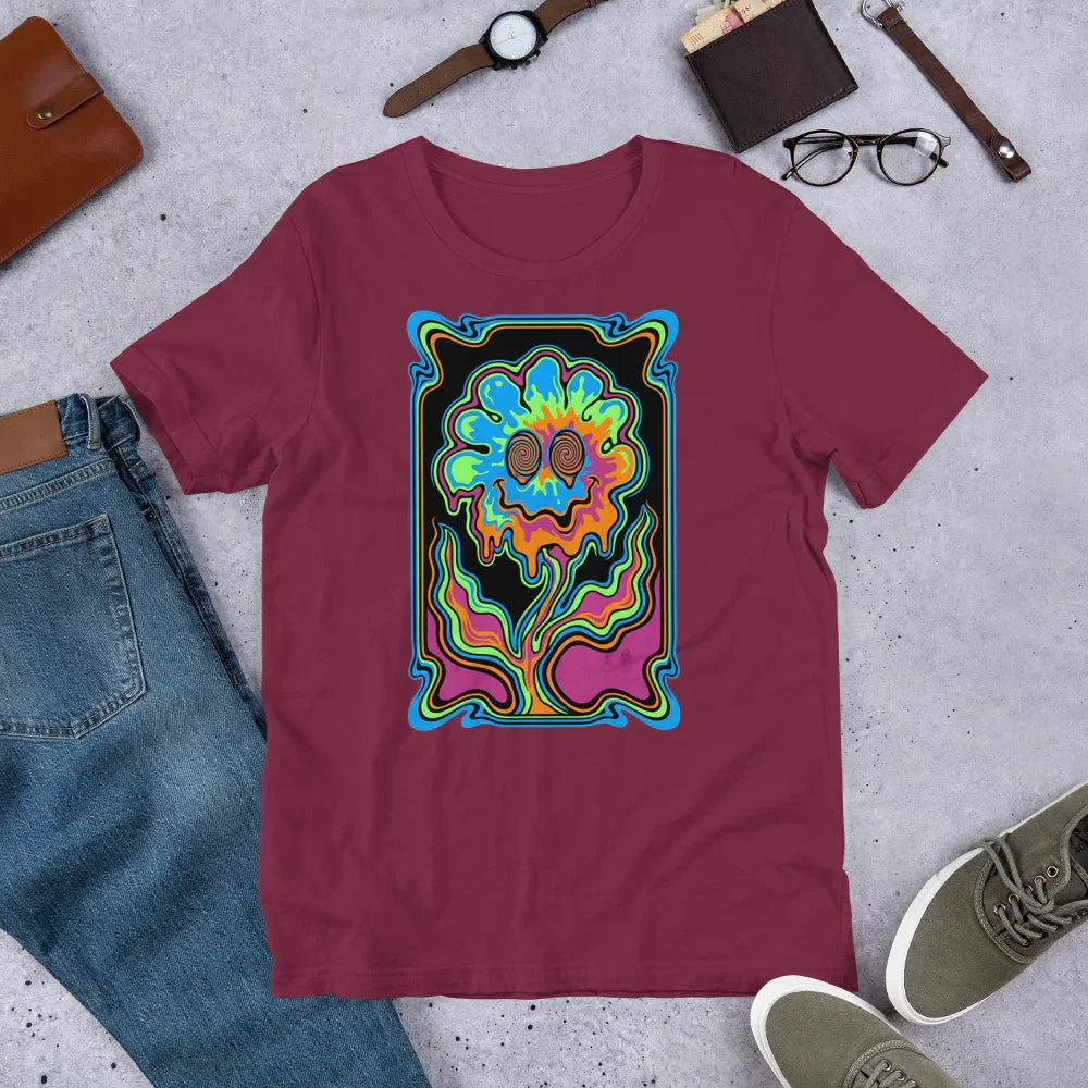 Maroon unisex staple t-shirt with vibrant psychedelic smiling flower design, paired with jeans, watch, glasses, and sneakers