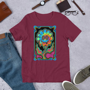 Maroon unisex staple t-shirt with vibrant psychedelic smiling flower design, paired with jeans, watch, glasses, and sneakers