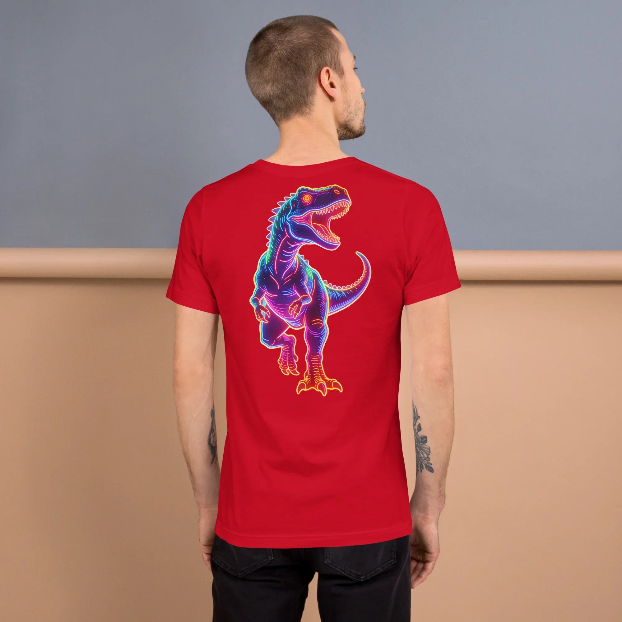 Man wearing red t-shirt with colorful neon dinosaur graphic on back in studio setting