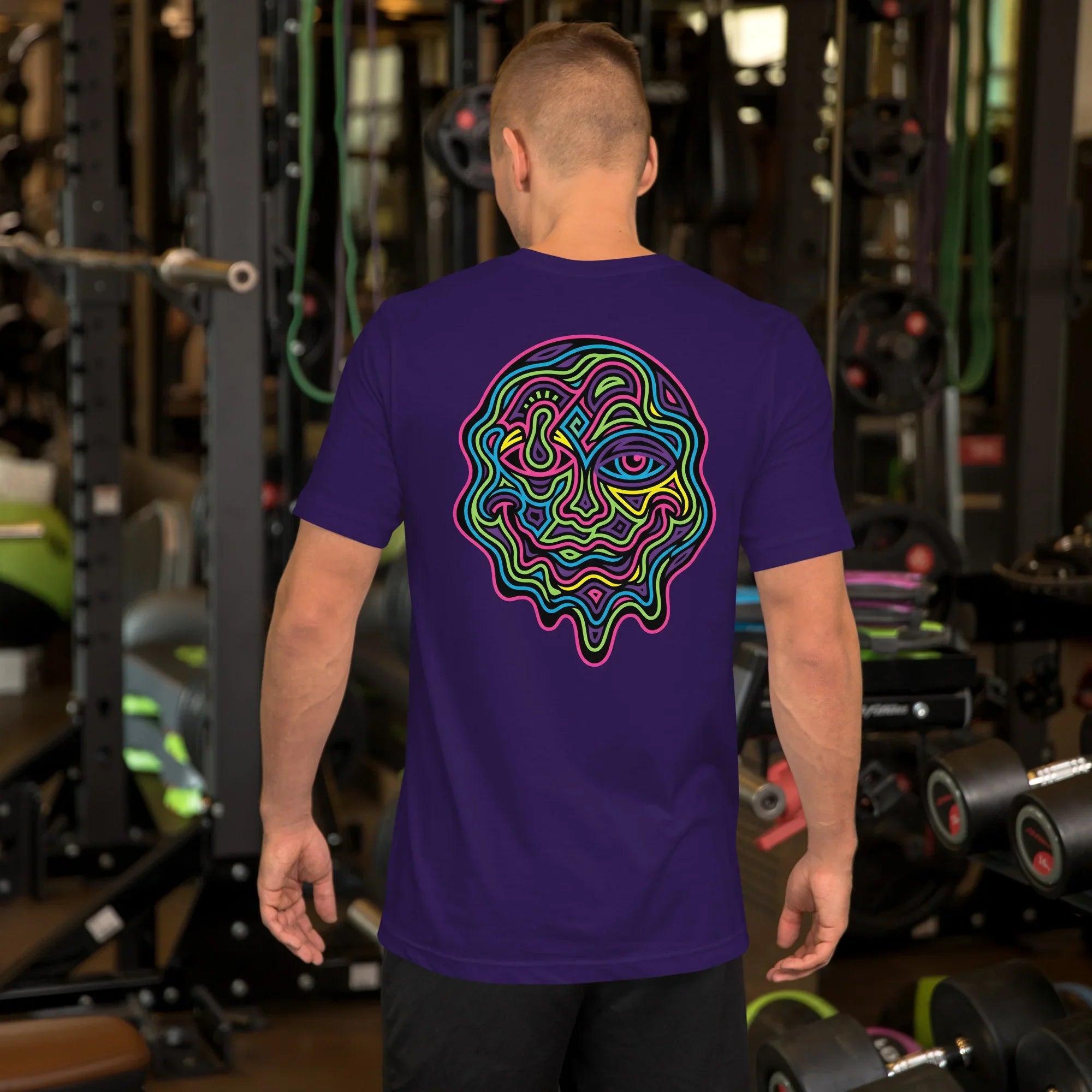 Man in gym wearing purple unisex t-shirt with vibrant psychedelic neon face design on back