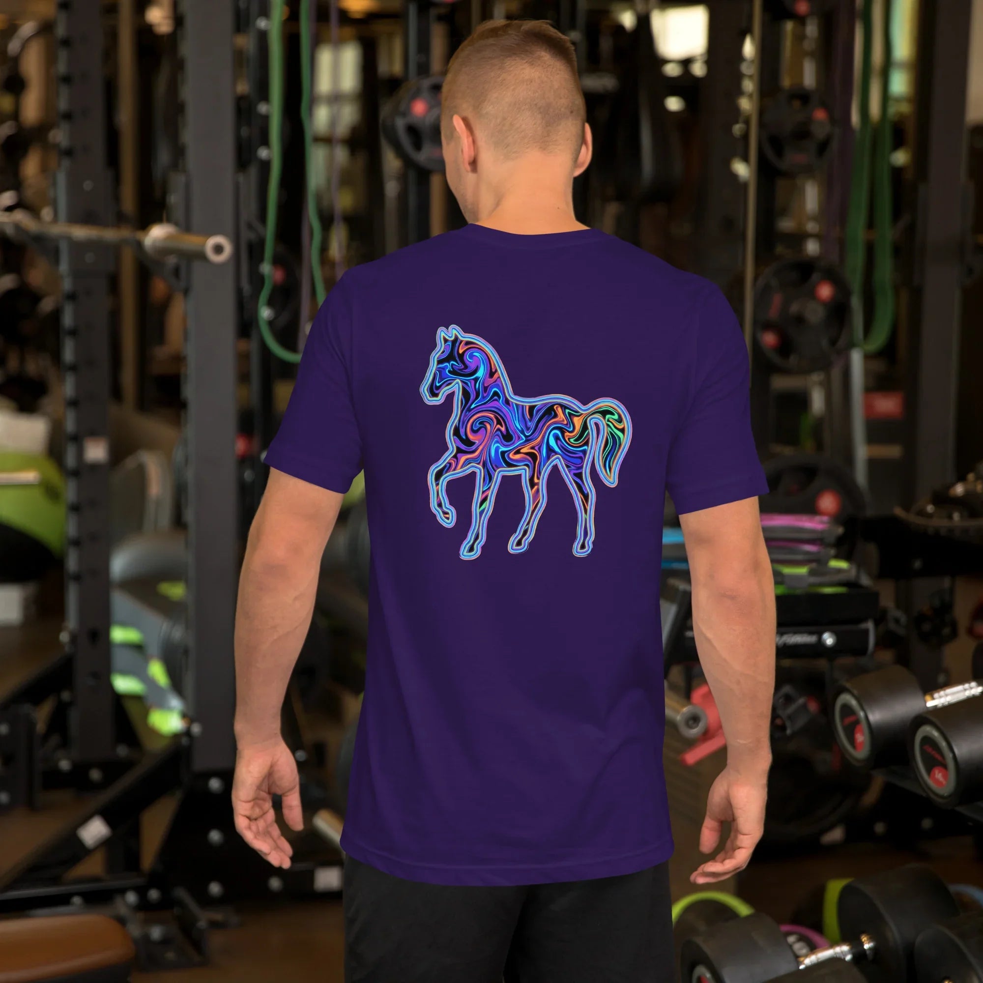 Man wearing purple unisex t-shirt with colorful psychedelic horse design on back, gym background