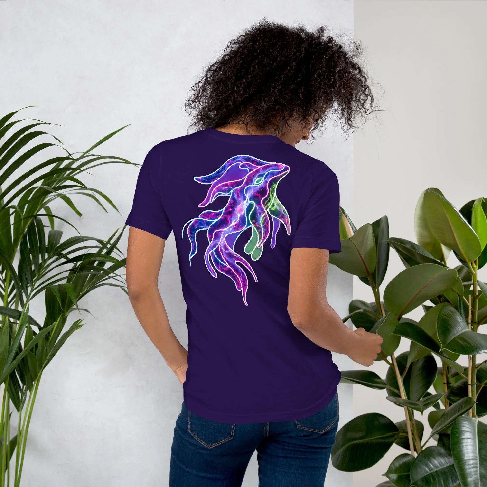 Woman wearing unisex purple t-shirt with neon psychedelic squid design on back in indoor plant setting