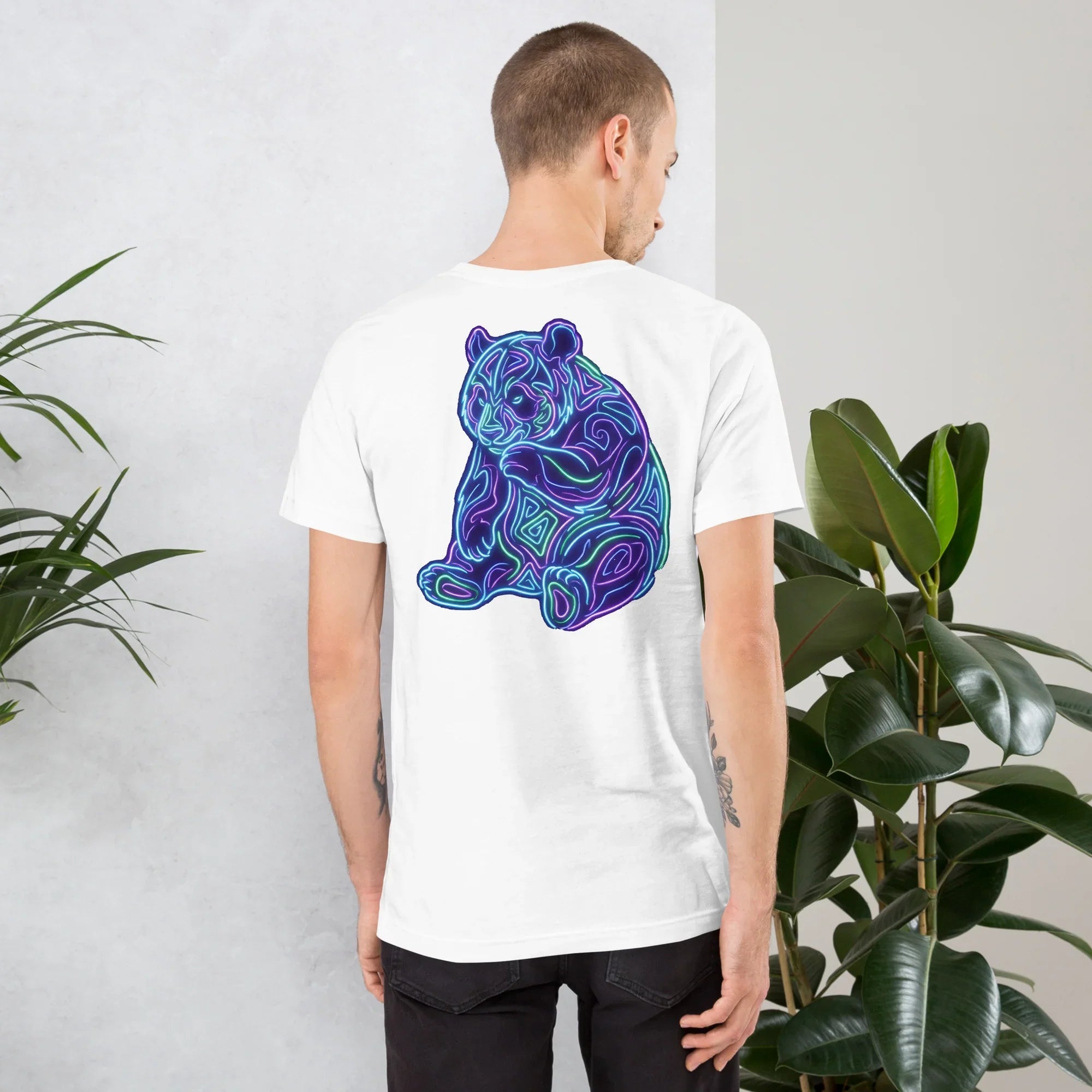 Man wearing white unisex T-shirt with vibrant neon psychedelic bear design on back in modern indoor setting